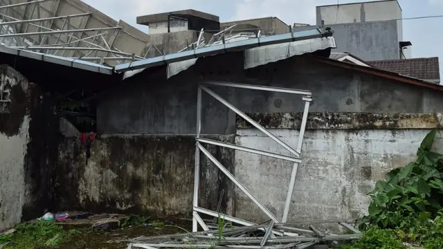 Atap bangunan sekolah yang tak digunakan terhempas angin kencang dan menimpa rumah warga di Kota Bogor. (Liputan6.com/Achmad Sudarno)