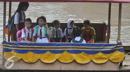 Sejumlah siswa SD menyeberangi sungai dengan perahu eretan untuk berangkat ke sekolah di Sungai Ciliwung, Jakarta, Senin, (4/1). Usai libur panjang para siswa kembali beraktivitas mengikuti tahun ajaran 2016-2017. (Liputan6.com/Gempur M Surya)