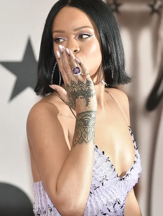 Hal tersebut terjadi pada pelantun lagu 'Umbrella', Rihanna. Ia tak sengaja mendapatkan hadiah yang dilempar oleh penggemar dari bawah panggung. (AFP/Bintang.com)