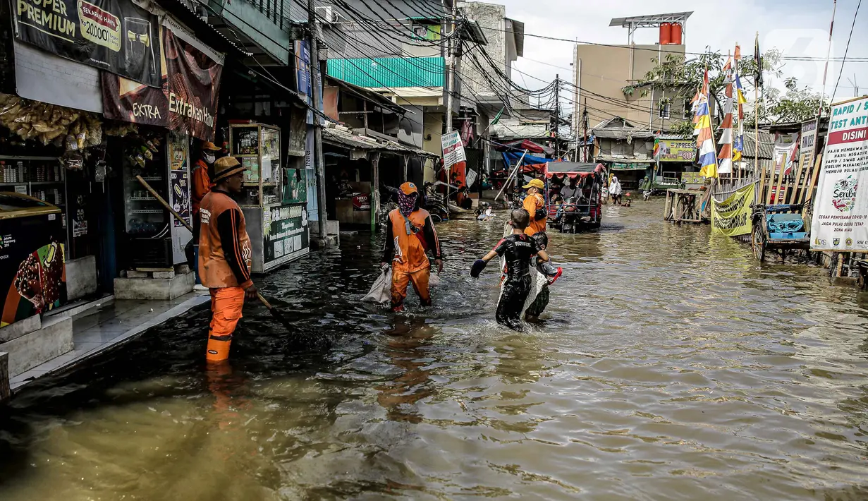 Petugas PPSU membersihkan sampah saat terjadi banjir rob di Pelabuhan Kali Adem, Muara Angke, Jakarta, Selasa (9/11/2021). Walau terendam banjir rob, petugas PPSU tetap sigap bersihkan sampah yang mengambang terbawa air laut. (Liputan6.com/Faizal Fanani)