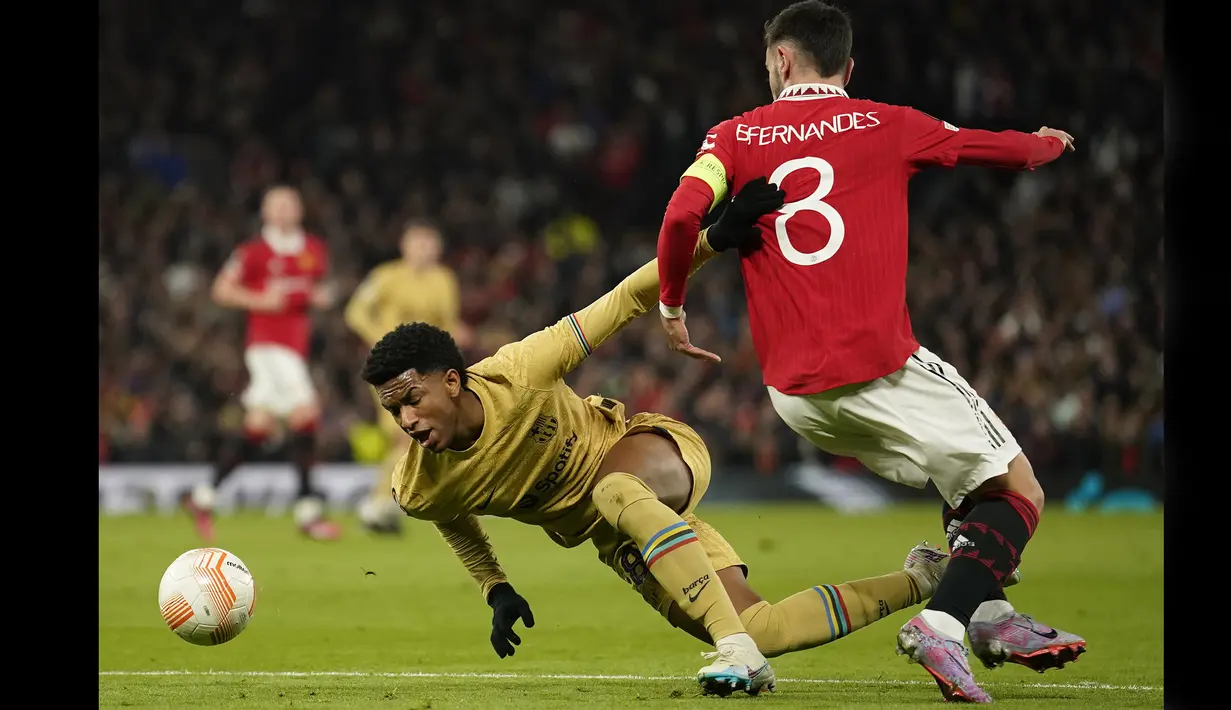 Pemain Manchester United, Bruno Fernandes (kanan) melanggar pemain Barcelona, Alejandro Balde yang membuahkan hadiah penalti Barcelona dalam pertandingan leg kedua play-off babak gugur Liga Europa 2022/2023 yang berlangsung di Old Trafford, Jumat (24/2/2023) WIB. (AP Photo/Dave Thompson)