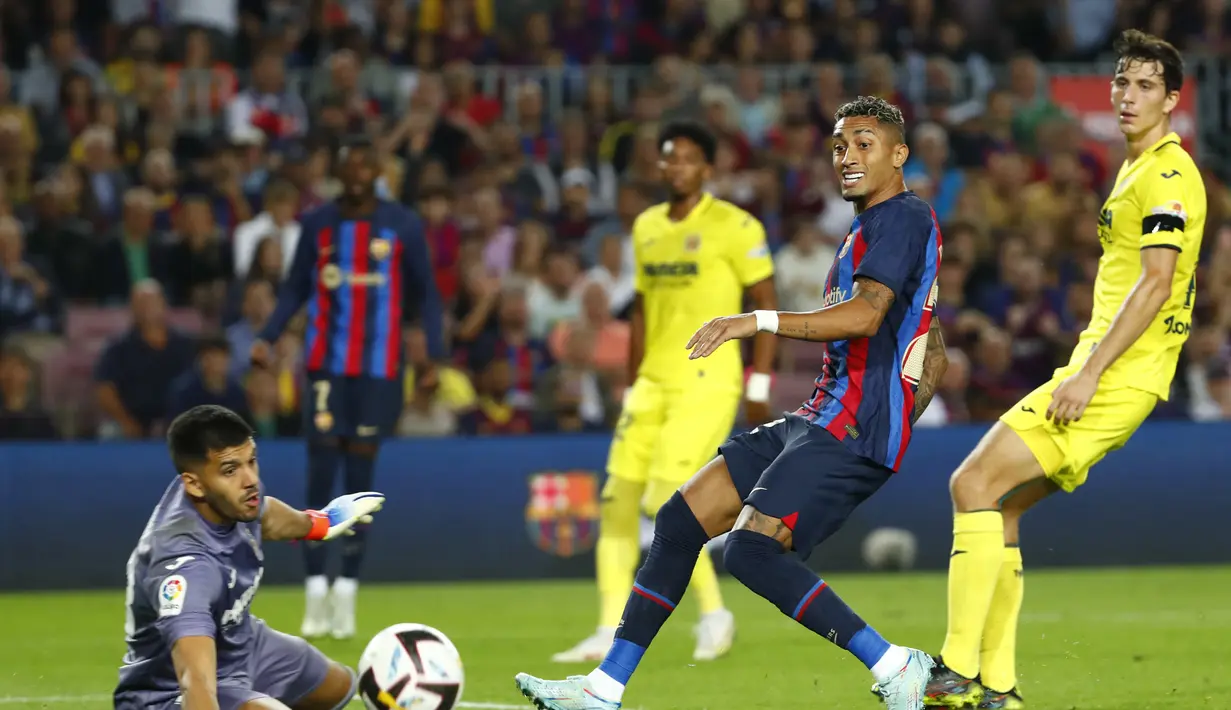 Penyerang Barcelona, Raphinha melepaskan tembakan ke arah gawang yang dijaga kiper Villareal, Geronimo Rulli menyaksikan selama pertandingan lanjutan La Liga Spanyol di stadion Camp Nou di Barcelona, Spanyol, Jumat (21/10/2022). Barcelona menang atas Villareal 3-0. (AP Photo/Joan Monfort)