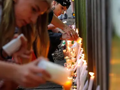 Para pelajar menyalakan lilin saat mengenang korban penembakan di luar Masjid Al Noor, Christchurch, Selandia Baru, Senin (18/3). Penembakan tersebut merupakan serangan terburuk dalam sejarah Selandia Baru modern. (AP Photo/Vincent Yu)