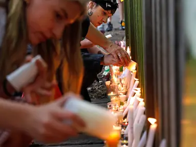 Para pelajar menyalakan lilin saat mengenang korban penembakan di luar Masjid Al Noor, Christchurch, Selandia Baru, Senin (18/3). Penembakan tersebut merupakan serangan terburuk dalam sejarah Selandia Baru modern. (AP Photo/Vincent Yu)