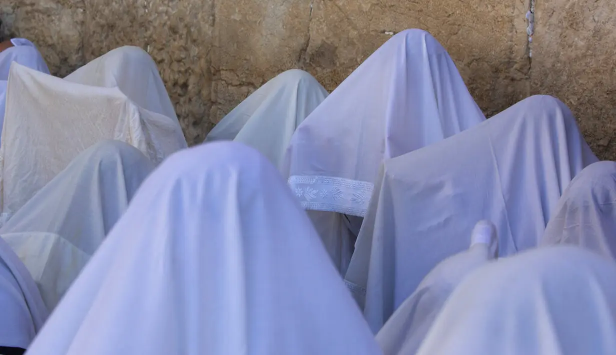 Pria Yahudi ultra-ortodoks dari kasta Cohanim Priestly berdoa dengan mengenakan selendang saat mereka berpartisipasi dalam pemberkatan selama hari raya Yahudi Sukkot di Tembok Barat, situs paling suci di Kota Tua Yerusalem, Rabu (22/9/2021).  (AP Photo/Sebastian Scheiner)