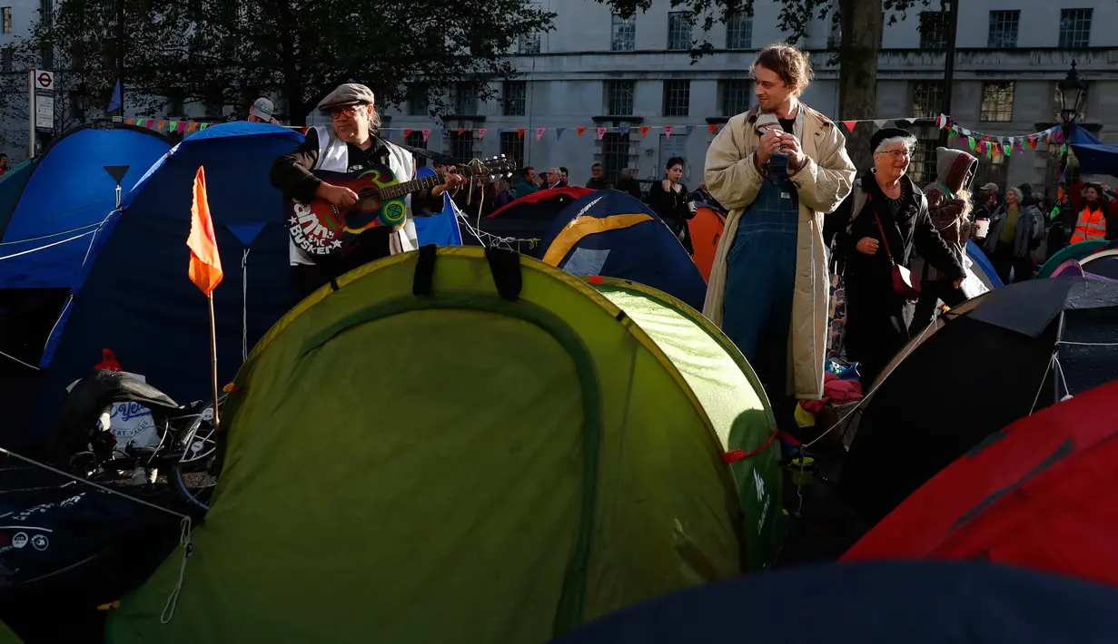 Seorang pria memainkan gitar saat aktivis iklim berkemah di Whitehall, London, Inggris, Selasa (8/10/2019). Protes global oleh gerakan Pemberontakan Kepunahan menuntut tindakan yang lebih mendesak untuk melawan perubahan iklim. (AP Photo/Alastair Grant) (AP Photo/Hibah Alastair)