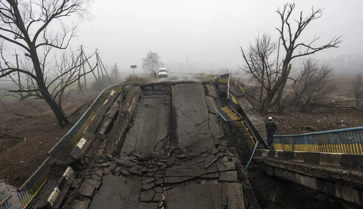 Seorang pria berdiri di samping jembatan yang dihancurkan oleh tentara Rusia saat mereka mundur dari desa-desa di pinggiran Kyiv, Ukraina, Jumat, 1 April 2022. Sejak Rusia menginvasi Ukraina pada 24 Februari 2022, kini perang yang berkecamuk memasuki hari ke-37. (AP Photo/Rodrigo Abd)