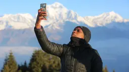 Seorang turis berswafoto di Bukit Poon yang terletak di Distrik Myagdi, Nepal (15/2/2020). Bukit Poon, yang juga dikenal sebagai Poon Hill, merupakan sebuah lokasi di sepanjang rute pendakian di wilayah Annapurna yang populer di kalangan wisatawan. (Xinhua/Zhou Shengping)