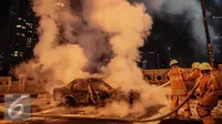 Petugas berusaha memadamkan api mobil yang terbakar di jalan layang Latuharhari, Jakarta, Kamis (18/9/2015). Diduga kebakaran akibat konsleting listrik yang terjadi dibagian depan kap mobil. (Liputan6.com/Faizal Fanani)