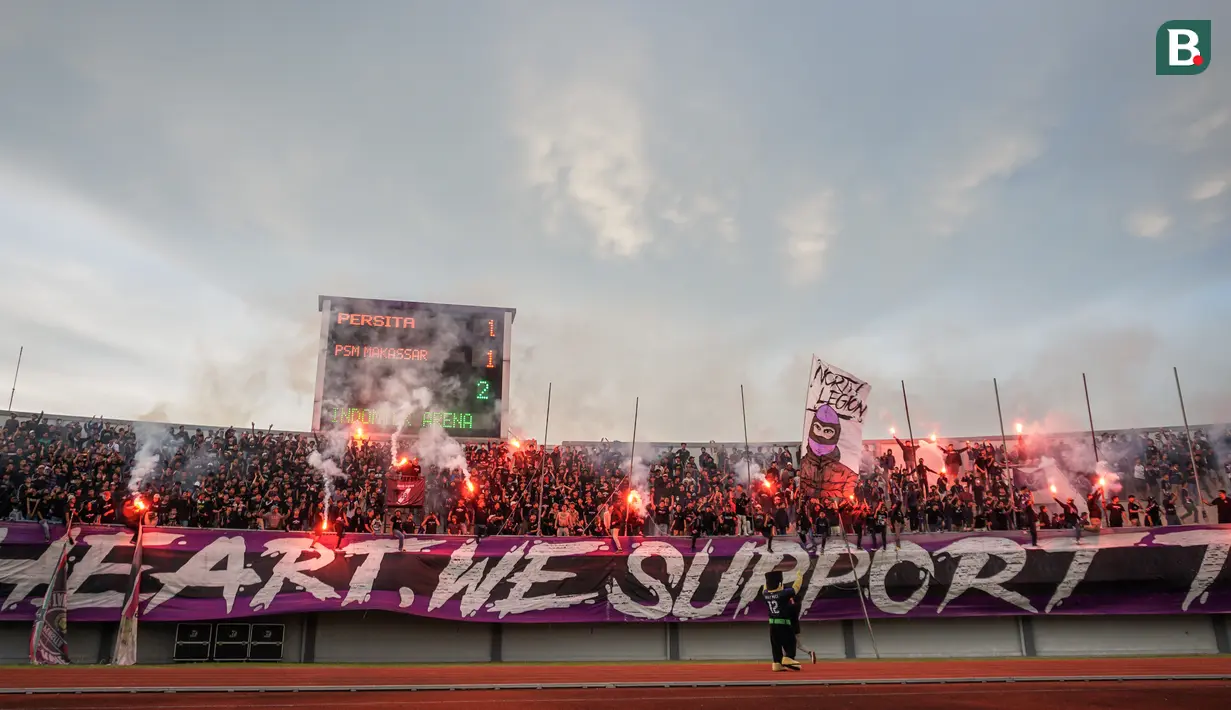 <p>Suporter Persita Tangerang memberikan dukungan terhadap timnya dengan menyalakan suar saat pertandingan persahabatan antara Persita Tangerang melawan PSM Makassar di Indomilk Arena, Tangerang, Rabu (01/06/2022). Pertandingan berakhir dengan skor imbang 1-1. (Bola.com/Bagaskara Lazuardi)</p>