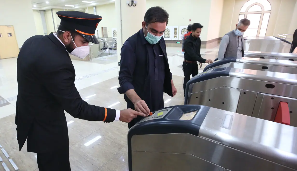 Staf memandu penumpang menggunakan mesin pemeriksaan tiket kereta di Lahore, Pakistan, 26 Oktober 2020. Layanan kereta metro pertama Pakistan, pada Minggu (25/10) mulai beroperasi secara komersial, membuka tahap baru sektor transportasi umum di negara Asia Selatan tersebut. (Xinhua/Liu Tian)