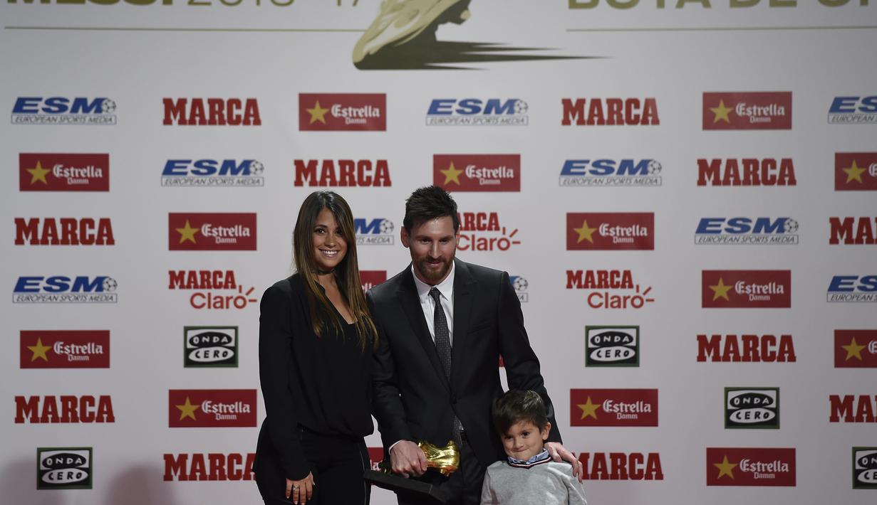 Lionel Messi melakukan sesi foto bersama istrinya, Antonella Roccuzzo dan Thiago usai menerima penghargaan sepatu emas Europa pada Golden Shoe awards 2017 di Antigua Fabrica Estrella Damm, Barcelona, (24/11/2017). (AFP/Josep Lago)