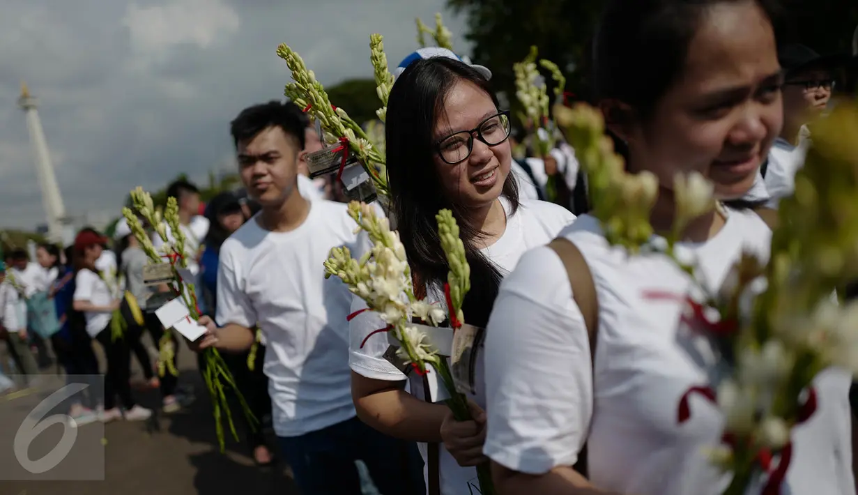 Gemabudhi membawa bunga yang akan dibagikan kepada pengguna jalan di depan Istana Negara, Jakarta, Sabtu (6/1). Aksi membagikan bunga sebanyak 2.561 tangkai itu dilakukan dalam rangka memperingati Hari Raya Trisuci Waisak. (Liputan6.com/Immanuel Antonius)