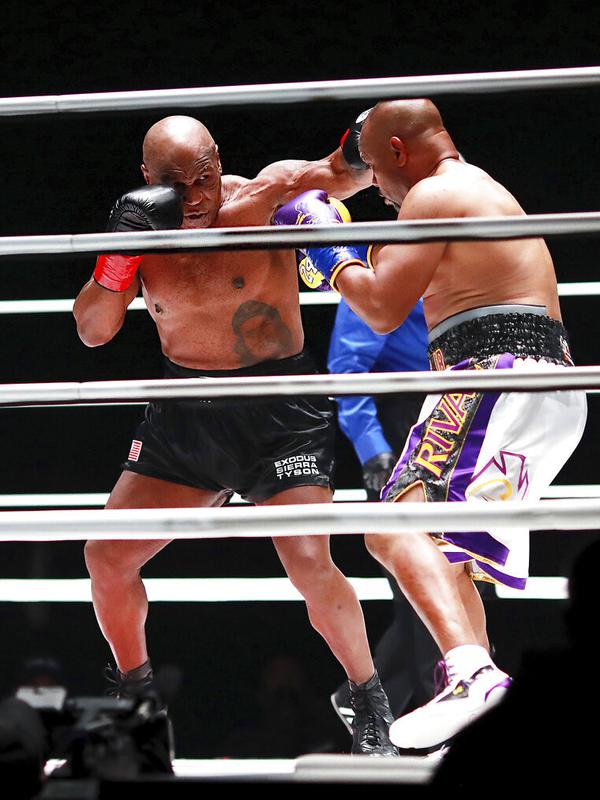 Mike Tyson melakukan pukulan terhadap Roy Jones Jr pada pertarungan tinju eksibisi di Los Angeles, Amerika Serikat, Sabtu (28/11/2020). Pertandingan berakhir tanpa pemenang alias imbang. (Joe Scarnici/Triller via AP)