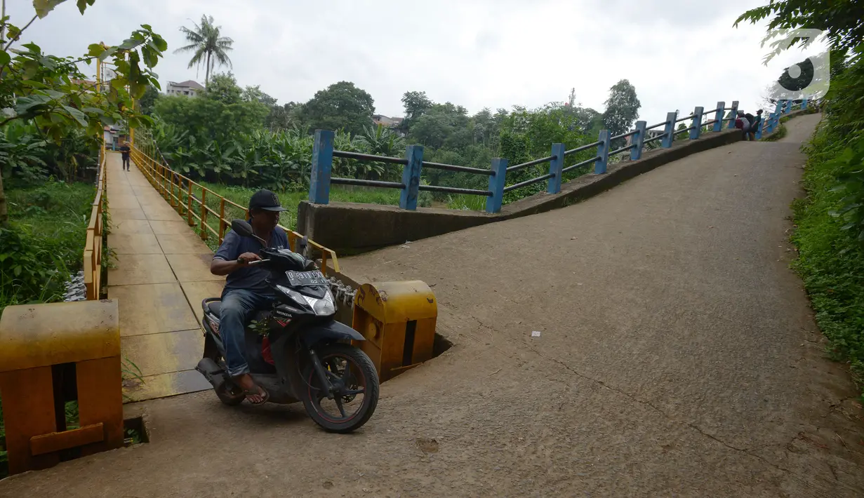 Pengendara motor melintasi jembatan gantung Kuning yang menghubungkan Pasar Minggu Poltangan ke Cililitan Condet, Jakarta, Selasa (28/12/2021). Jembatan gantung Kuning tersebut merupakan jalan umum dan akses jalan warga yang ingin berlalu-lalang. (merdeka.com/Imam Buhori)
