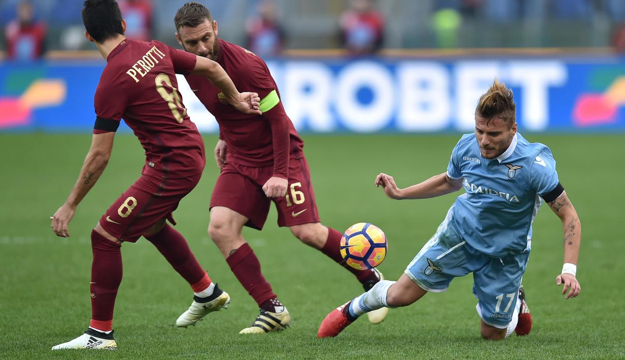 Pemain Lazio, Ciro Immobile (kanan) dihadang dua pemain AS Roma, Daniele De Rossi (tengah) dan Diego Perotti pada laga Derby della Capitale di Olympic Stadium, Roma, Italia, (4/12/2016). AS Roma menang 2-0.  (AFP/Alberto Pizzoli)