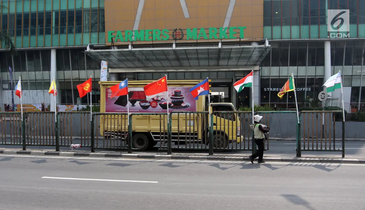 Deretan bendera negara-negara kontestan Asian Games 2018 yang terpasang menggunakan bambu di pagar pembatas Jalan Pluit Selatan Raya, Jakarta, Kamis (19/7). Pemasangan bendera yang diikat di tiang bambu menjadi kontroversi. (Liputan6.com/Arya Manggala)