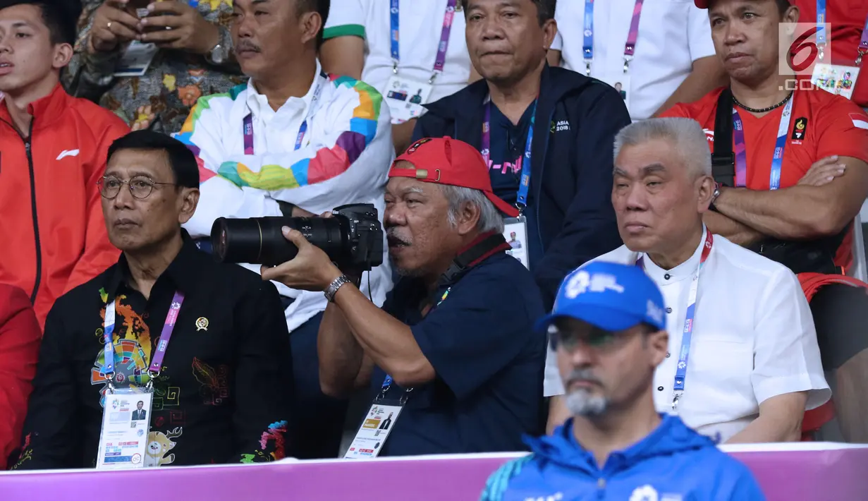 Menteri PUPR, Basuki Hadimuljono bersiap mengabadikan momen saat laga semifinal bulu tangkis beregu putra Asian Games 2018, Indonesia melawan Jepang di Jakarta, Selasa (21/8). Indonesia unggul dan lolos ke final. (Liputan6.com/Helmi Fithriansyah)