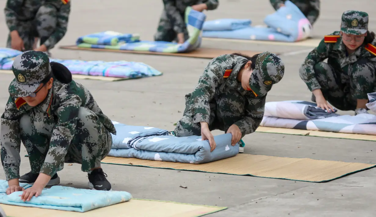 Mahasiswa baru belajar melipat selimut selama sesi pelatihan militer di sebuah kampus di Yangzhou, Jiangsu, China, Jumat (6/9/2019). Pelatihan militer bagi mahasiswa baru di China  biasanya dilakukan pada akhir liburan musim panas. (STR/AFP)