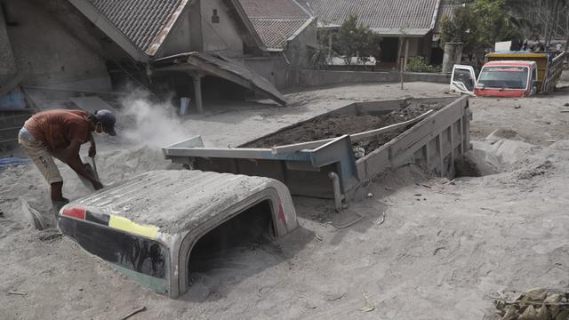 Seorang pria memeriksa truk yang tertimbun abu vulkanik pascaerupsi Gunung Semeru di Lumajang, Jawa Timur, 5 Desember 2021. Tiga jenazah ditemukan di dalam truk pasir yang terjebak erupsi Gunung Semeru.  (AP Photo/Trisnadi)