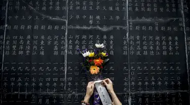 Seikat bunga diletakkan di monumen yang berisi nama-nama orang yang gugur dalam pertempuran melawan Jepang saat Perang Dunia II di Nanjing, (3/9/2014). (AFP PHOTO/STR)