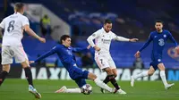 Striker Real Madrid, Eden Hazard (kanan) berebut bola dengan bek Chelsea, Andreas Christensen pada laga leg kedua semifinal 2020/2021 di Stamford Bridge, London (5/5/2021). Eden Hazard mampu meraih trofi Liga Champions bersama Real Madrid pada musim 2021/2022. Ia hanya tampil dalam 3 laga di Liga Champions musim 2021/2022 dan tak dimainkan pada laga final saat menang 1-0 atas Liverpool. (AFP/Glyn Kirk)