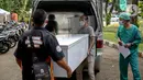 Petugas memindahkan peti jenazah COVID-19 untuk didistribusikan ke rumah sakit di TPU Petamburan, Jakarta, Selasa (6/7/2021). Dalam sehari, 100-200 peti jenazah didistribusikan ke sejumlah rumah sakit di DKI Jakarta. (Liputan6.com/Faizal Fanani)