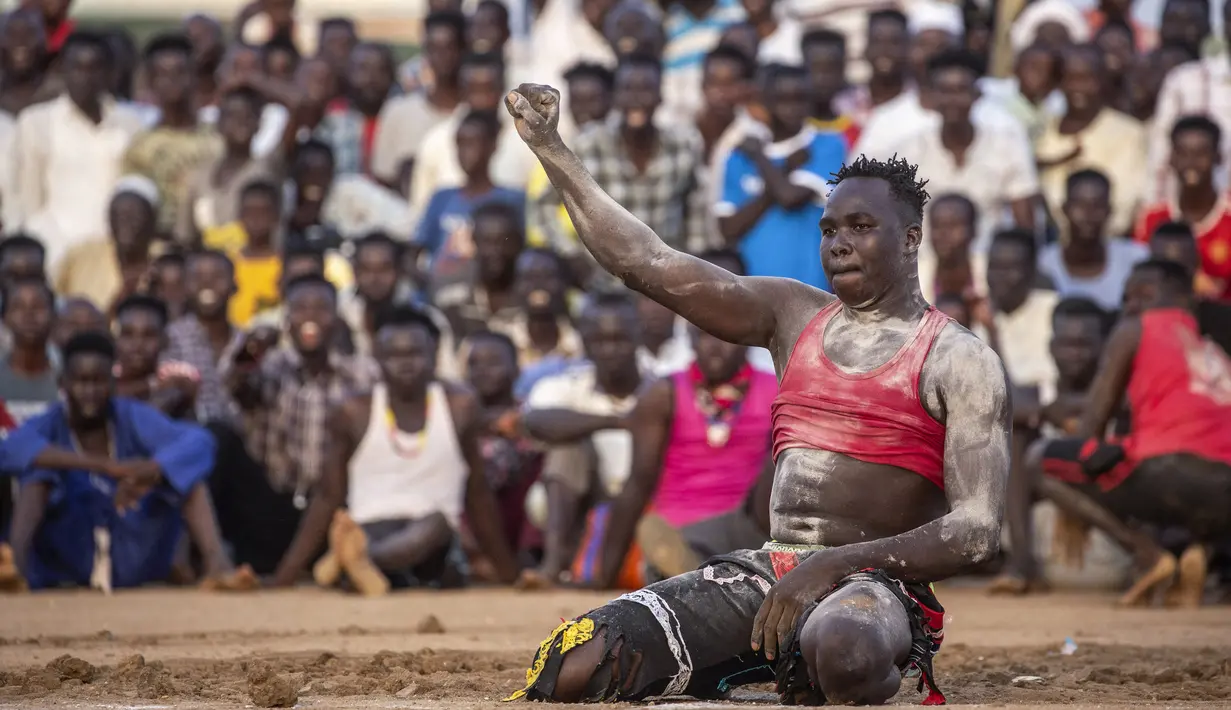 Pegulat pemenang mengangkat tinjunya ke udara dalam kompetisi gulat tradisional Nuba antara tim dari daerah Haj Youssef dan Omdurman di Ibu Kota Khartoum, Sudan, 30 Juli 2021. (Abdulmonam EASSA/AFP)