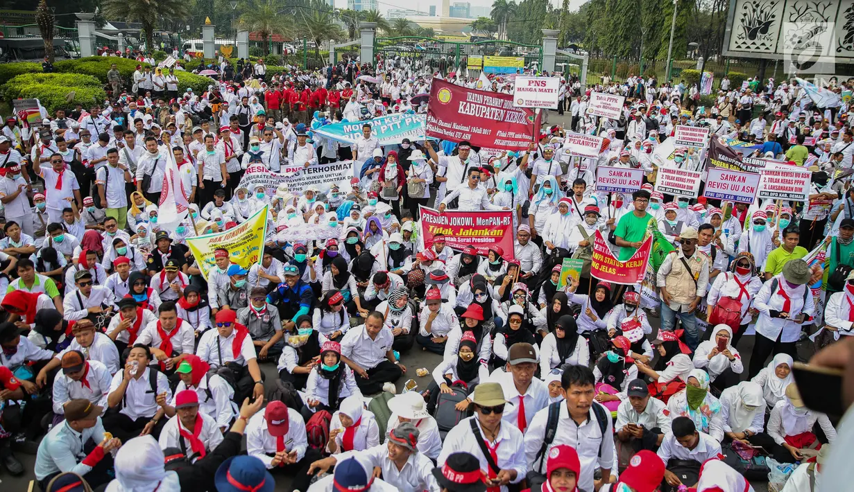 Massa membawa berbagai atribut dalam aksi damai di depan Istana Negara, Jakarta, Rabu (19/7). Mereka mendesak agar para pegawai non PNS yang telah mengabdi pada garda depan pelayanan publik, bisa diangkat menjadi PNS. (Liputan6.com/Faizal Fanani)