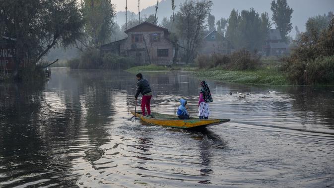 Seorang pria Kashmir bersama anak-anaknya mendayung perahunya di danau Dal di Srinagar, Kashmir yang dikuasai India (18/10/2020). (AP Photo/Dar Yasin)
