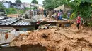 Warga melihat tempat di mana tim penyelamat mencari korban setelah rumah runtuh setelah hujan lebat di distrik Attecoube di Abidja, Pantai Gading (16/6/2022). Enam orang tewas semalam setelah hujan lebat memicu tanah longsor di ibu kota ekonomi Pantai Gading Abidjan, kata layanan darurat. (AFP/Issouf Sanogo)