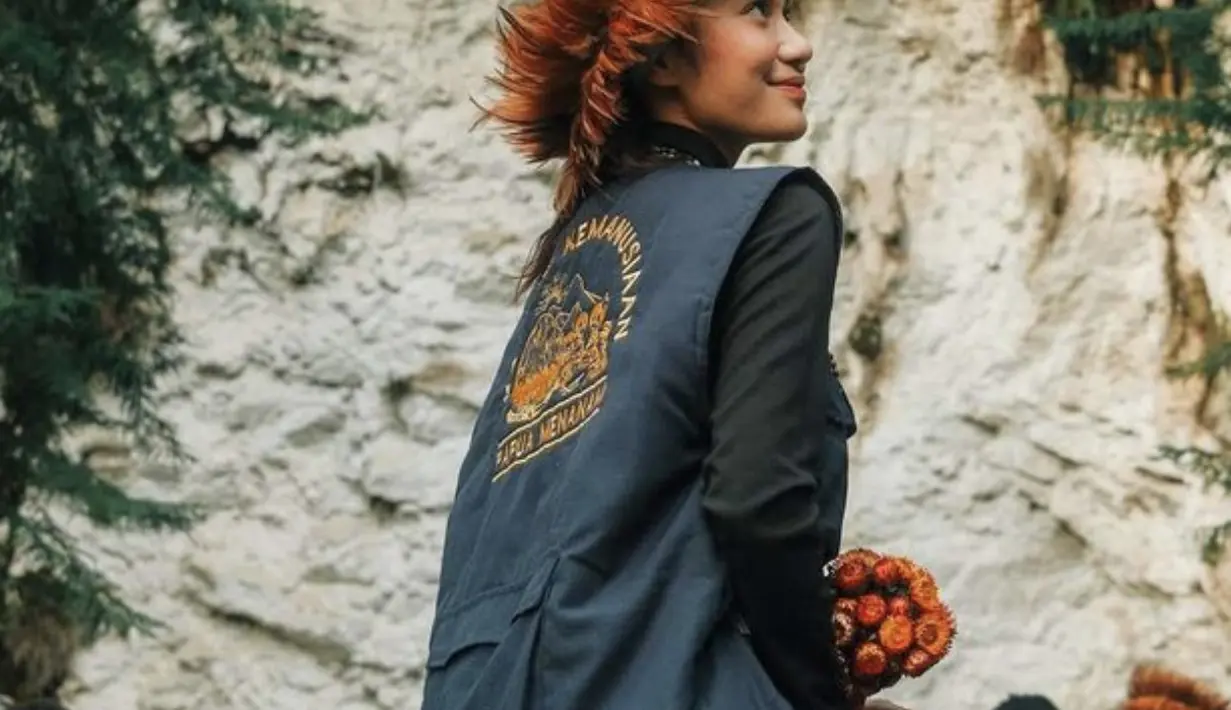 Ia tampik dengan mengenakan topi khas Papua. [Foto: Azizah Salsha]