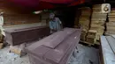 Herman pengrajin peti mati sedang mengecat pelitur untuk pembuatan peti mati di Pondok Kelapa, Jakarta Timur, Rabu (6/5/2020). Peti untuk jenazah Covid-19, terbuat dari aluminium foil dengan harga Rp 900 ribu untuk ukuran dewasa dengan panjang sekitar 100-200 cm. (merdeka.com/Imam Buhori)