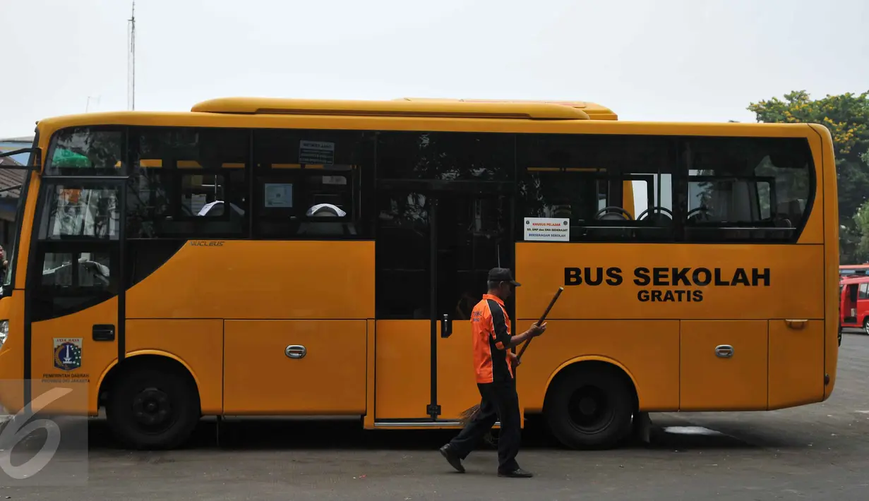Petugas menyapu di dekat bus sekolah yang parkir di Terminal Pasar Minggu, Jakarta, Senin (26/10). Gubernur DKI Basuki Tjahaja Purnama berencana menghapus bus sekolah. Sebagai gantinya, pelajar digratiskan naik Transjakarta. (Liputan6.com/Gempur M Surya)