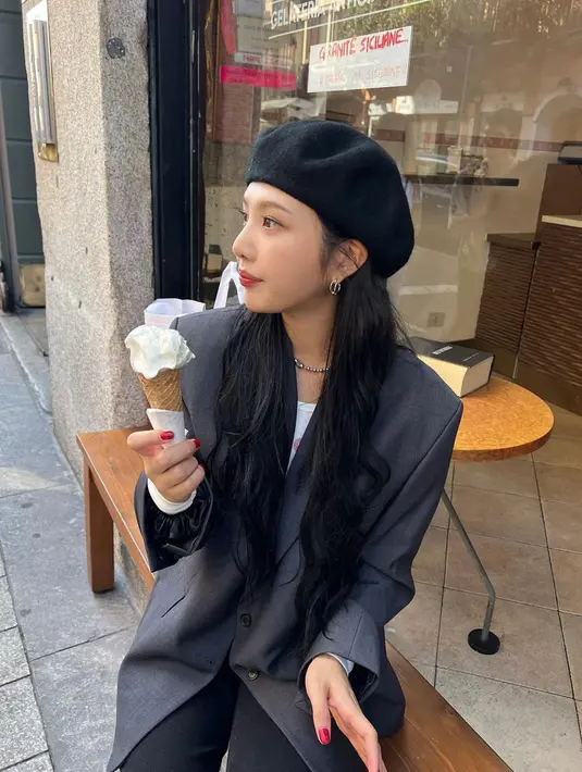 Joy saat mengenakan blazer berwarna abu sambil memakan es krim di depan sebuah toko. Penyanyi tersebut mempercantik penampilannya dengan tambahan topi. (Instagram/@_imyour_joy)