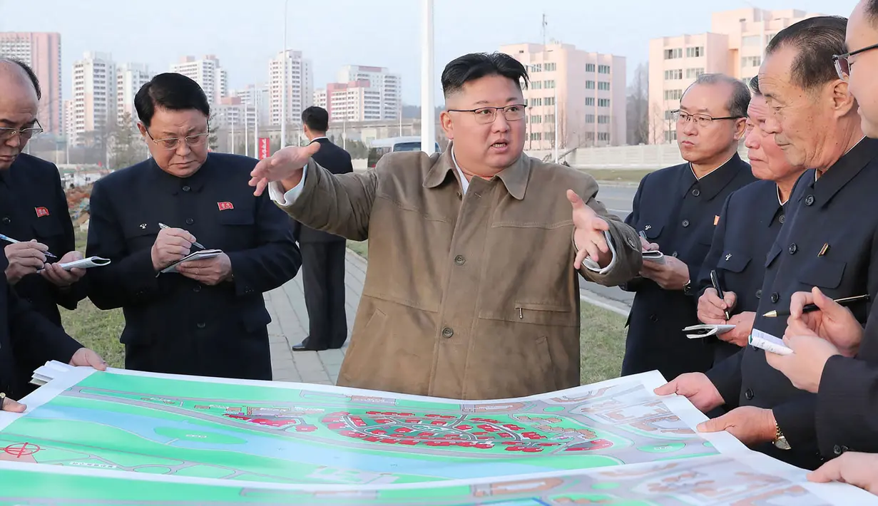 Pemimpin Korea Utara Kim Jong-un memberikan arahan kepada stafnya saat mengunjungi lokasi konstruksi pembangunan gedung apartemen di tepi Sungai Pothong, Korea Utara, Kamis (1//4/2021)..( STR/KCNA VIA KNS/AFP)