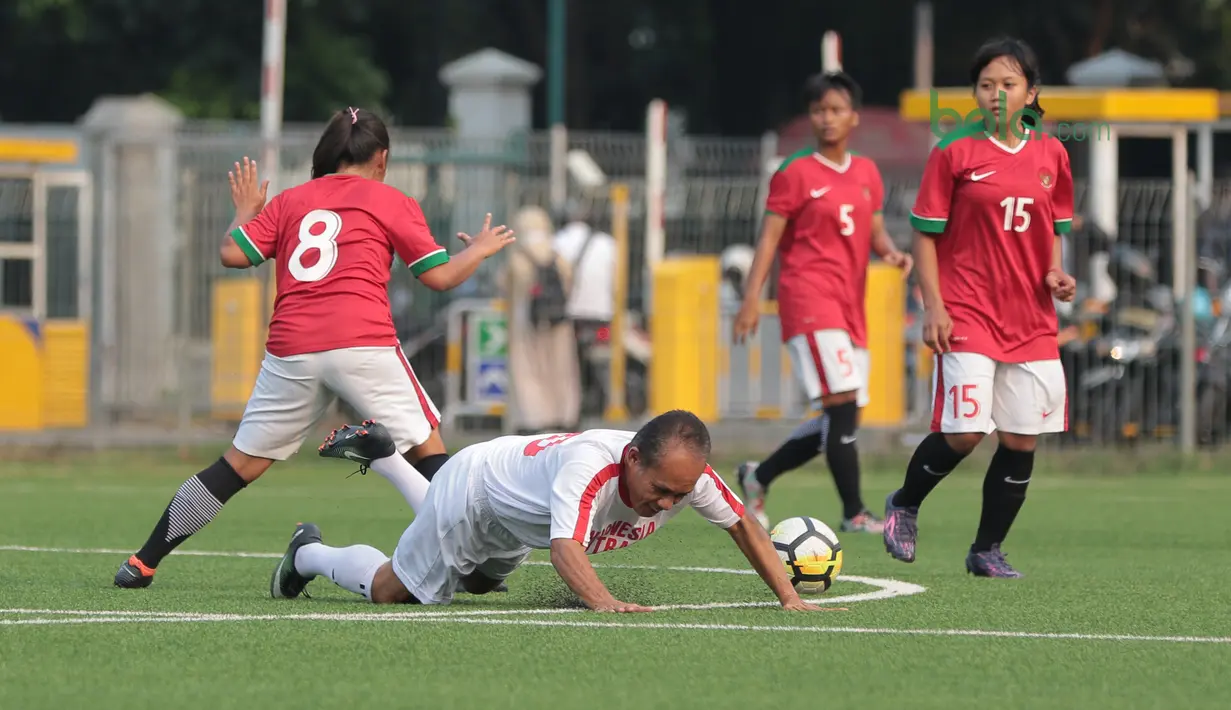 Legenda Indonesia, Zulkarnain Lubis jatuh saat berebut bola dengan pemain Timnas Wanita Indonesia, Susi Susanti (kiri) pada laga uji coba di Lapangan ABC Senayan, Jakarta, Kamis (5/4/2018). Timnas Wanita Indonesia menang 3-2. (Bola.com/Nick Hanoatubun)