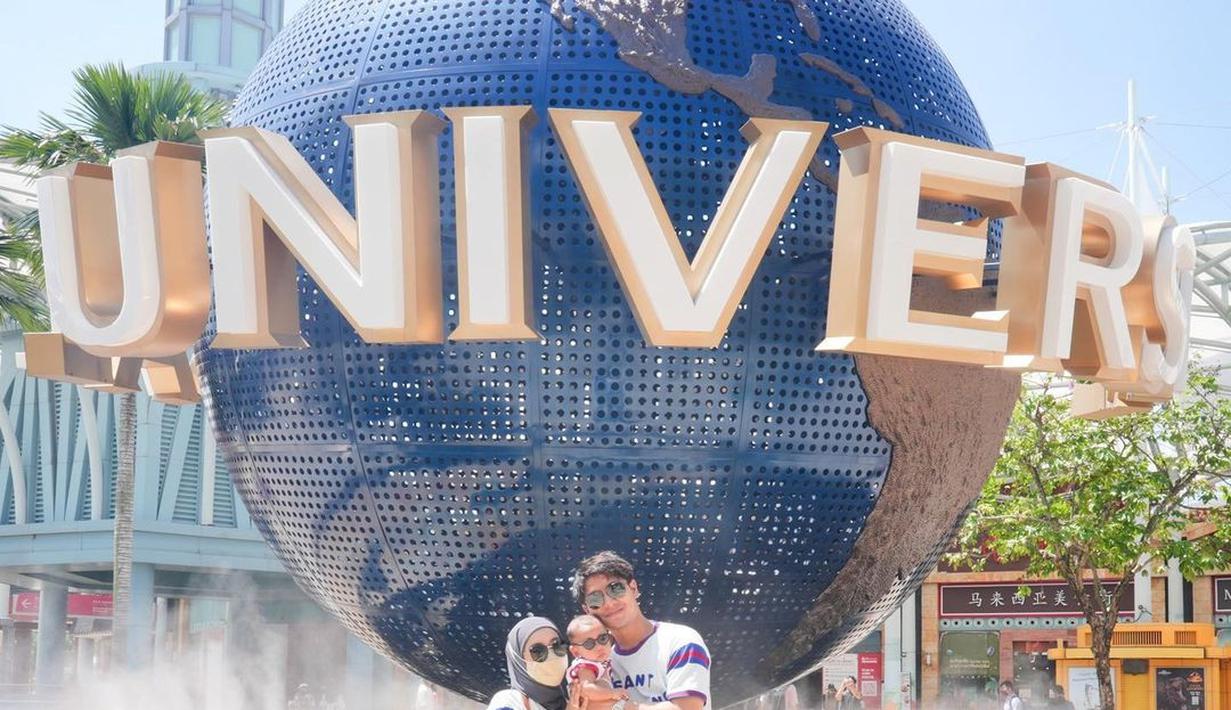 Rizky Billar dan Lesti Kejora memilih Singapura untuk liburannya, tak berbeda dengan yang lain, mereka juga membawa Baby L. Mereka pun berpose di bola dunia Universal yang menjadi ciri khas para turis.  (Foto: Instagram/@rizkybillar)