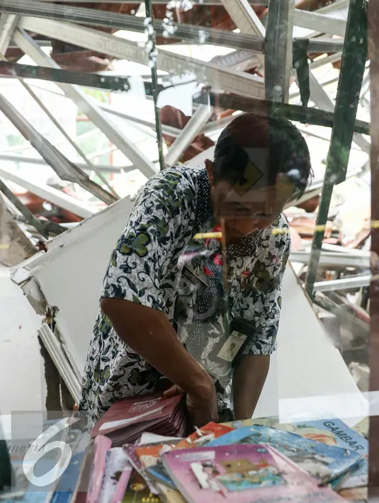 Guru SDN Kalibaru 6 menyelamatkan buku dan dokument penting di ruang kelas yang ambruk, Cilodong, Jawa Barat, Jumat (26/2/2016). Sebanyak 4 ruangan kelas dan guru di SDN Kalibaru 6 ambruk karena tingginya curah hujan. (Liputan6.com/Yoppy Renato)