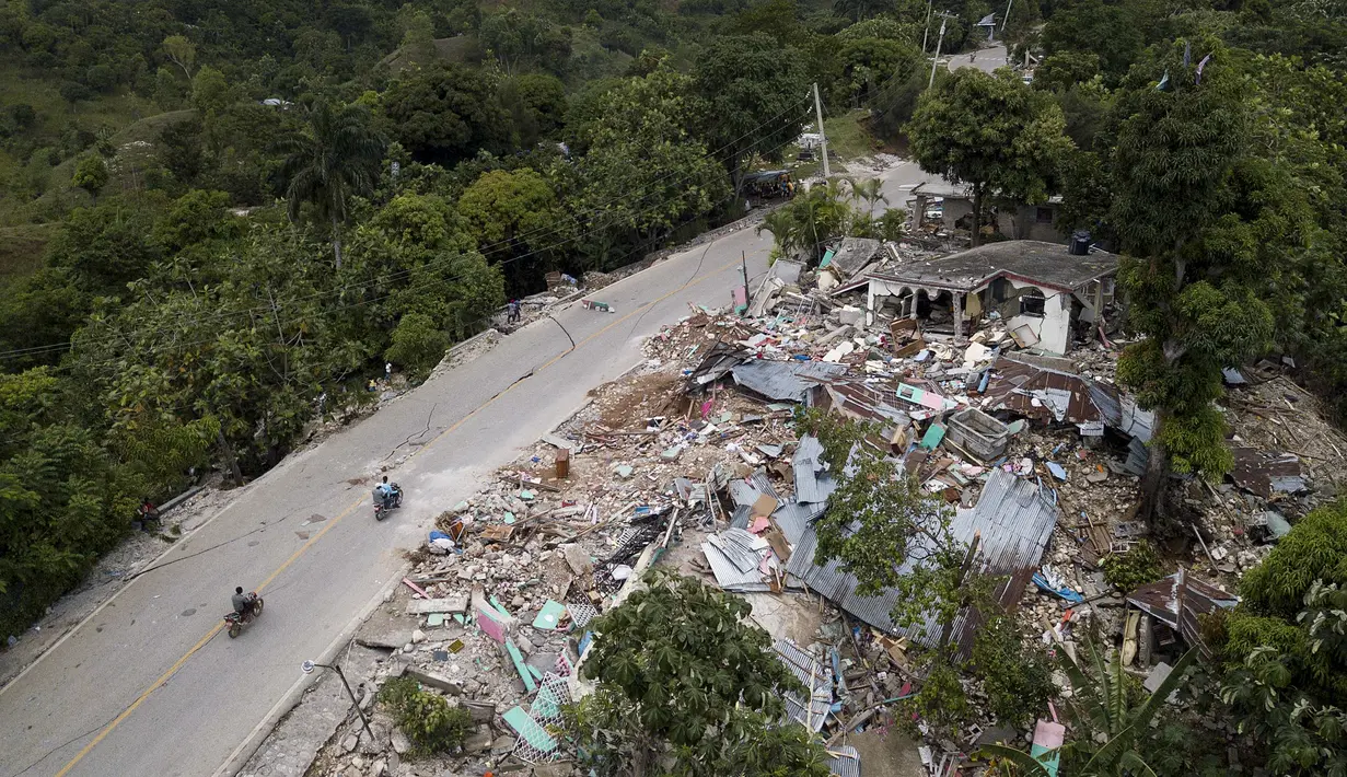 Rumah-rumah tergeletak di reruntuhan di sepanjang jalan yang rusak, empat hari setelah gempa berkekuatan 7,2 melanda bagian barat daya negara itu, di Rampe, Haiti, Rabu (18/8/2021). Korban jiwa akibat gempa di Haiti Sabtu pekan lalu terus bertambah menjadi 1.941 orang. (AP/Matias Delacroix)