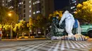 Pengirim mengenakan pakaian pelindung membawa tas makanan di gerbang komunitas perumahan di Shanghai, China (11/4/2022). AS telah memerintahkan semua staf konsuler non-darurat untuk meninggalkan Shanghai, yang berada di bawah penguncian ketat untuk menahan lonjakan COVID-19. (AP Photo)