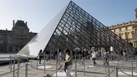Pengunjung tiba di piramida Louvre yang dirancang arsitek China Ieoh Ming Pei, pintu masuk ke Museum Louvre di Paris (6/7/2020). Presiden dan direktur Louvre Jean-Luc Martinez mengatakan, krisis coronavirus telah menyebabkan "lebih dari 40 juta euro dalam kerugian di Louvre. (AFP/Francois Guillot)