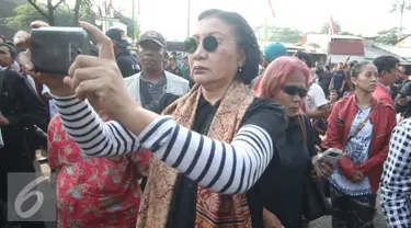 Aktivis Ratna Sarumpaet mengabadikan gambar saat penertiban pemukiman penduduk di kawasan Rawajati, Jakarta, Kamis (1/9). Keberadaan Ratna di lokasi tersebut guna membantu mediasi warga yang rumahnya dieksekusi petugas. (Liputan6.com/Immanuel Antonius)