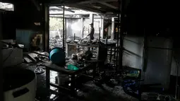 Seorang petugas forensik memeriksa bangunan asrama sekolah yang hangus terbakar di Thailand utara, Senin (23/5). 17 siswi tewas setelah kebakaran menghanguskan asrama sekolah untuk anak-anak suku pedalaman miskin itu. (REUTERS/Athit Perawongmetha)
