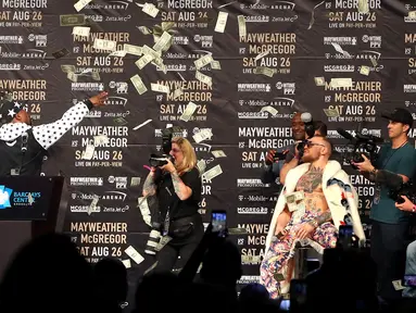 Petinju Floyd Mayweather melemparkan uang ke arah Conor McGregor saat konferensi pers tur dunia jelang pertandingannya di Barclays Center, Brooklyn, (13/7). Duel ini akan digelar di Las Vegas pada 26 Agustus. (Mike Lawrie/Getty Images/AFP)