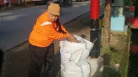 Dalam rangka merayakan Hari Peduli Sampah Nasional, seorang nenek di Makassar, mengumpulkan sampah yang berceceran di jalan. (Liputan6.com/Eka Hakim)