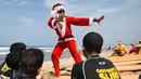 Seorang pria berkostum Santa Claus memberikan pelatihan selancar kepada sejumlah anak di Pantai Kuta, Bali, Senin (10/12). Setiap tahunnya, ribuan wisatawan mendatangi Bali saat menjelang natal dan tahun baru. (AFP PHOTO / Sonny Tumbelaka)