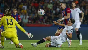 Striker Barcelona, Robert Lewandowski (kanan) melepaskan tendangan yang berusaha diblok gelandang Sevilla, Juanlu Sanchez pada laga pekan ke-8 Liga Spanyol 2023/2024 di Olympic Stadium, Montjuic, Barcelona, Sabtu (30/9/2023) dini hari WIB. (AP Photo/Joan Monfort)