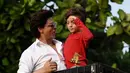 Aktor Bollywood, Shah Rukh Khan menggendong putranya, Abram Khan menyapa para fans yang berkumpul di depan rumahnya pada perayaan Idul Fitri di Mumbai, Rabu (5/6/2019). Ribuan penggemar kerap berkumpul di depan rumah Shah Rukh Khan di momen-momen tertentu. (SUJIT JAISWAL/AFP)