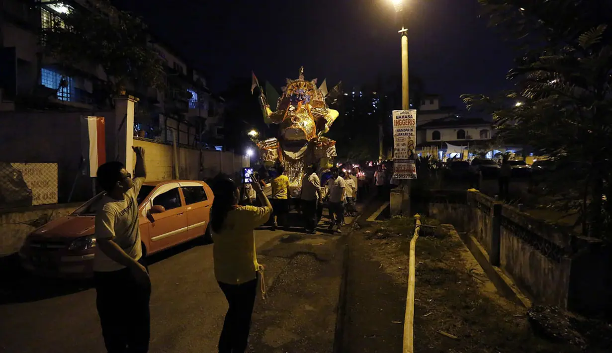 Beberapa orang membawa membawa patung ke lubang api di festival Hungry Ghost, Kuala Lumpur, (3/8/2014). (REUTERS/Olivia Harris)